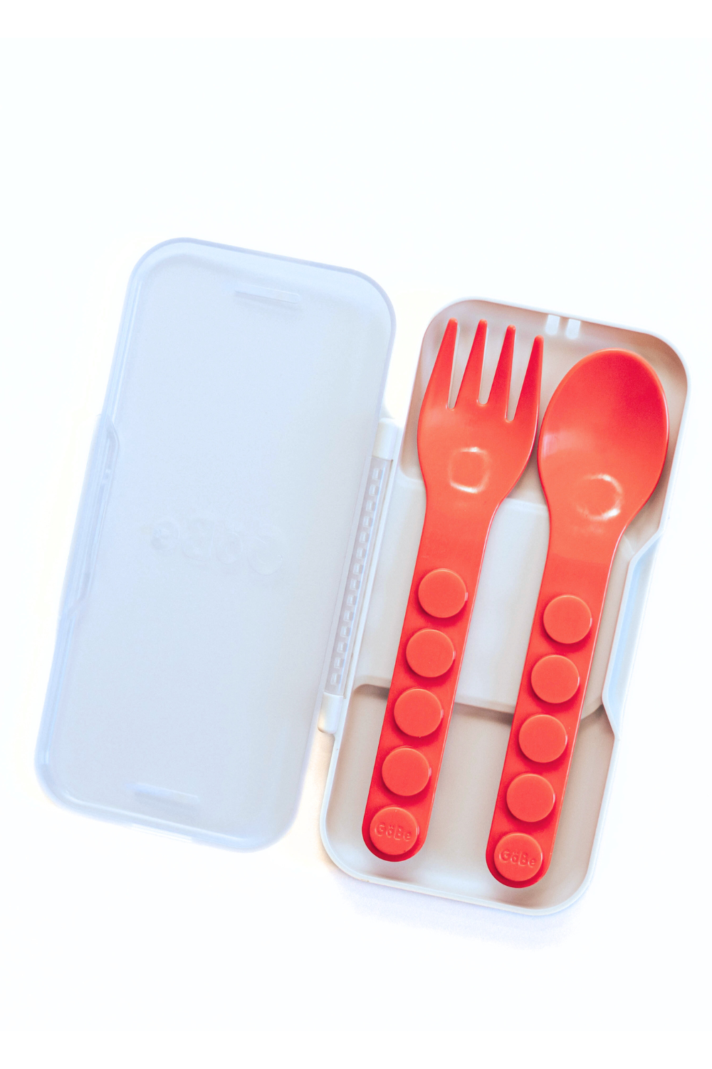Red plastic fork and spoon set in a clear case on a white background