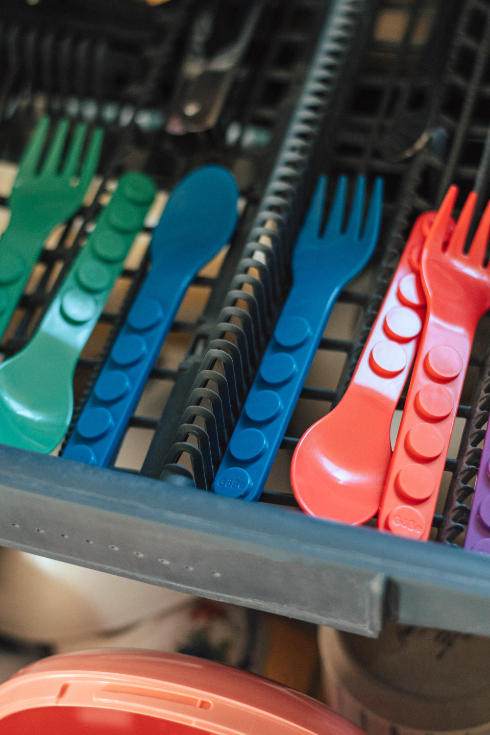 Colorful plastic cutlery set in a dishwasher.