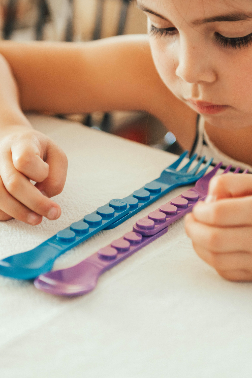 Child playing with colorful plastic utensils on a table